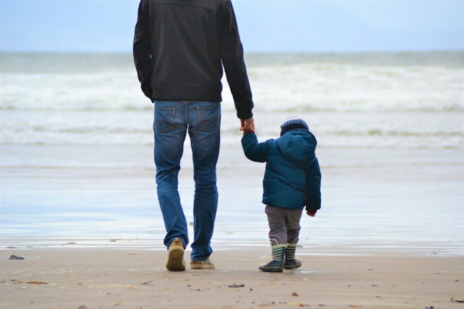 Father and young son walking hand in hand on a beach, representing child custody cases in Roanoke VA