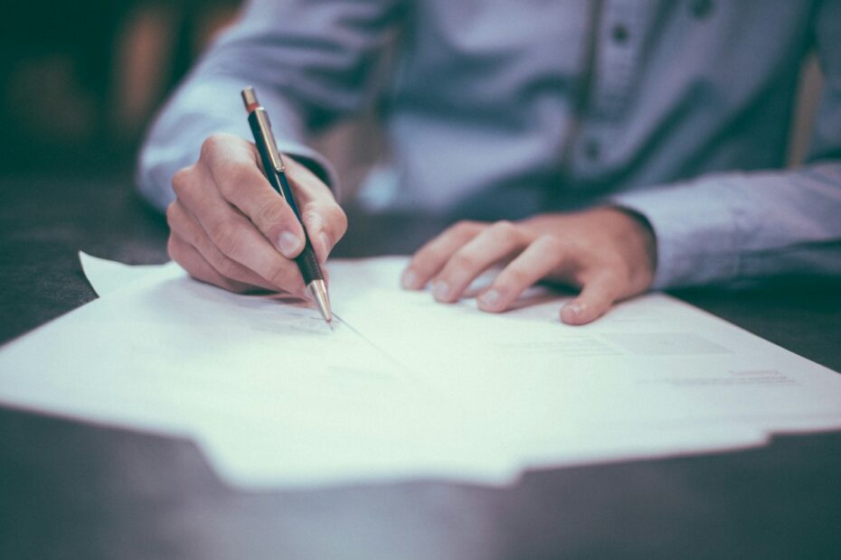 Person signing a document at a desk, representing mistakes to avoid in a Virginia divorce